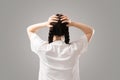 A woman with dark hair and pigtails and grabs her head. Rear view. The concept of stress and psychology