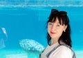 Woman, dark-haired, European, middle-aged, stands in front of a blue aquarium Royalty Free Stock Photo