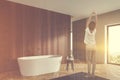 Woman in dark wooden bathroom with tub Royalty Free Stock Photo