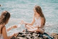 Woman with daughter bilds stones pyramid on seashore on a sunny day on the blue sea background. Happy family holidays Royalty Free Stock Photo