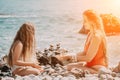 Woman with daughter bilds stones pyramid on seashore on a sunny day on the blue sea background. Happy family holidays Royalty Free Stock Photo