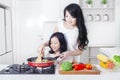 Woman and daughter cooking vegetable