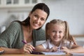 Woman and daughter drawing with felt-tip look at camera