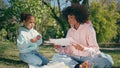 Woman daughter eating picnic on green lawn close up. African family weekend