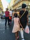 Woman and daughter stroll down Paris street among diverse crowd