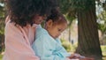 Woman daughter watching cartoon on smartphone sitting green meadow close up. Royalty Free Stock Photo