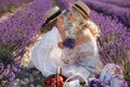 Woman with daughter in white dresses having fun in lavender field in summer. family portraits