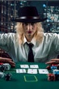 Woman dealer in hat with playing cards and poker chips in casino watching the game Royalty Free Stock Photo