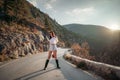 The woman is dear to the mountains. A woman in a white sweater, black boots and a hat walks along a winding alpine path Royalty Free Stock Photo