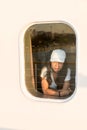 Woman looking out window of ferry boat with white hat Royalty Free Stock Photo