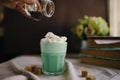 Woman decorate with colored edible sparkles green mint coffee. Milk shake, cocktaill, frappuccino.