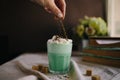 Woman decorate with colored edible sparkles green mint coffee. Milk shake, cocktaill, frappuccino.