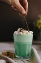 Woman decorate with colored edible sparkles green mint coffee. Milk shake, cocktaill, frappuccino.