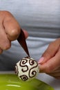 A woman decorates with the help of dark chocolate popcake glazed with white chocolate Royalty Free Stock Photo
