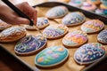 Woman decorating Easter gingerbread cookies with colorful glaze, closeup