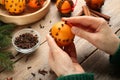 Woman decorating fresh tangerine with cloves at wooden table, closeup. Making Christmas pomander balls Royalty Free Stock Photo