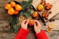 Woman decorating fresh tangerine with red ribbon at wooden table, top view. Making Christmas pomander balls Royalty Free Stock Photo