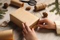 Woman decorating gift box at white wooden table, closeup. Christmas present Royalty Free Stock Photo