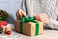 Woman decorating gift box at white wooden table, closeup. Christmas present Royalty Free Stock Photo