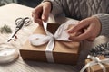 Woman decorating gift box at white wooden table, closeup. Christmas present Royalty Free Stock Photo