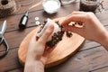 Woman decorating handmade candle with coffee beans at wooden table