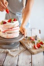Process of decorating meringue cake with whipped cream and fresh strawberry