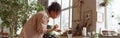 Woman decorator making green ikebana on tray in florist workshop