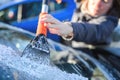 Woman deicing car windshield with ice scraper Royalty Free Stock Photo