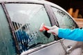 Woman deicing side car windshield with scraper