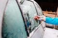 Woman deicing side car windshield with scraper Royalty Free Stock Photo