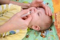 The woman deletes slime from a nose to the sick crying baby with a nasal aspirator