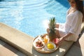 Young woman with delicious breakfast on tray near swimming pool, closeup. Space for text Royalty Free Stock Photo