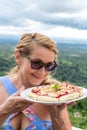 Woman with delicious strawberry pizza on a balinese tropical nature background. Bali island, Indonesia.