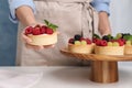 Woman with delicious tartlets at white table, closeup