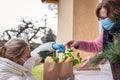 Woman delivering food to elderly person during coronavirus lockdown Royalty Free Stock Photo