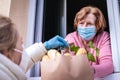 Woman delivering groceries and food to her senior mother with face mask Royalty Free Stock Photo