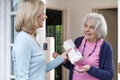 Woman Delivering Newspaper To Elderly Neighbour