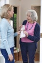 Woman Delivering Newspaper To Elderly Neighbour