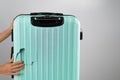 A woman demonstrates a broken suitcase on a white background. Damaged baggage during the flight.