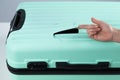 A woman demonstrates a broken suitcase on a white background. Damaged baggage during the flight.