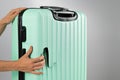 A woman demonstrates a broken suitcase on a white background. Damaged baggage during the flight.