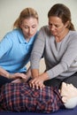 Woman Demonstrating CPR On Training Dummy In First Aid Class