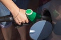 A woman in denim blue shorts with a fuelling nozzle pouring gasoline into the tank of the car at the filling station