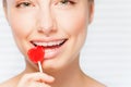 Woman with dental braces biting red lollipop