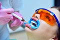 Woman dentist applies whitening gel to patient teeth