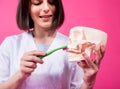 Woman dentist brushing teeth of an artificial skull using a single tufted toothbrush