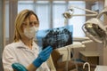 Woman dentist in clinic stares at x-ray image of tooths