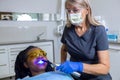 Woman dentist doing dental curing light setting composite resins for female patient Royalty Free Stock Photo