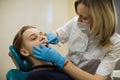 Woman dentist doing teeth checkup of boy in a dental chair at medical clinic. Royalty Free Stock Photo