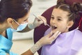 Woman dentist examining smiling child girls teeth with mirror in dental clinic Royalty Free Stock Photo